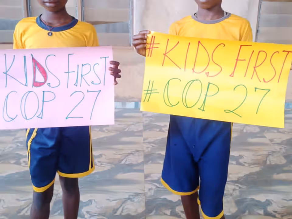 Zwei Schulkinder halten jeweils ein Schild hoch