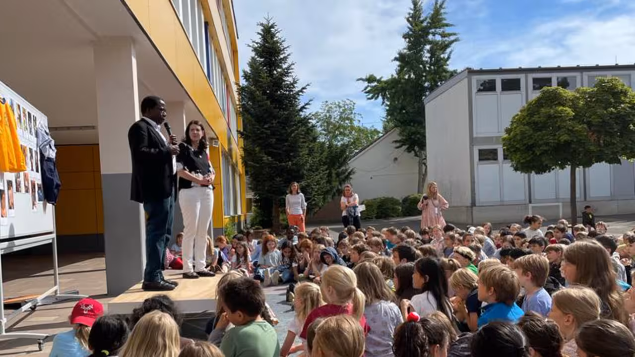 Kinder sitzen auf dem Boden und hören einem Redner zu