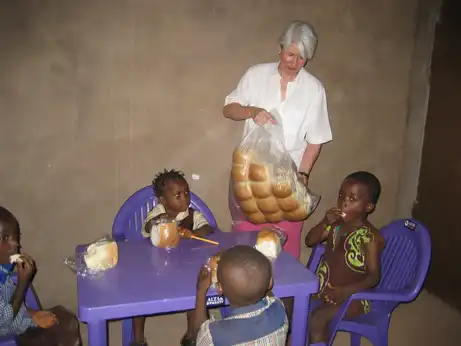 Kinder sitzen auf Stühlen und essen Brot