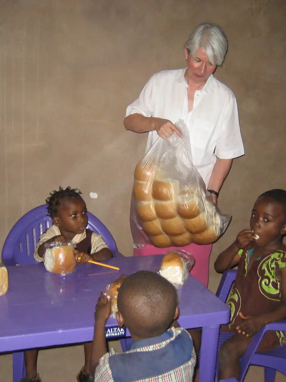 Kinder sitzen auf Stühlen und essen Brot